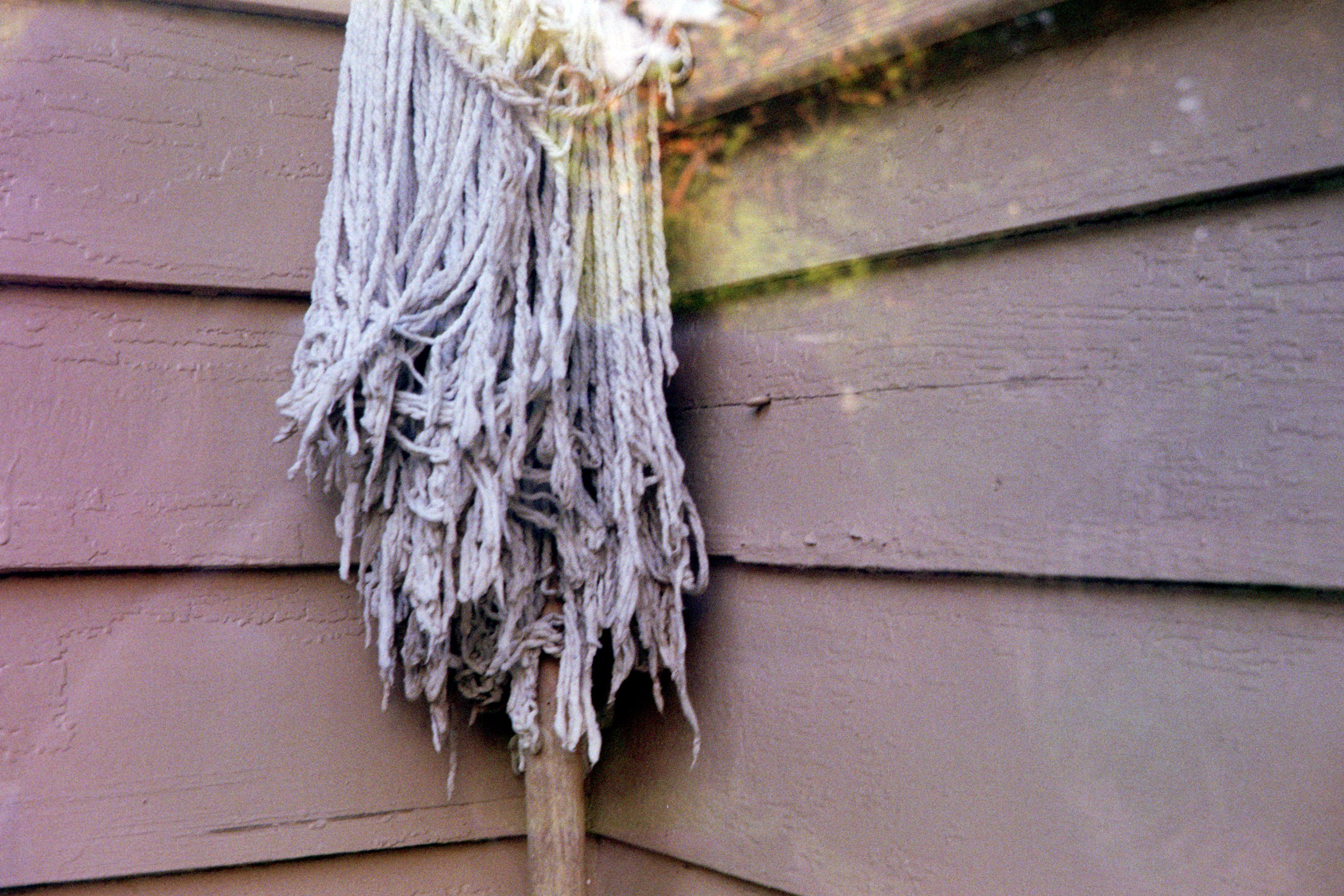 A mop standing against the wall, through a glass door